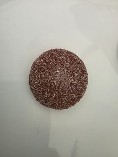 Customer's reddish-brown, textured Moroccan Oil Shampoo Bar on a white surface.