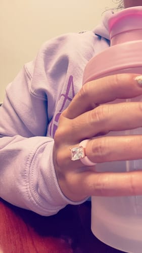 Customer showing a close-up of the emerald-cut GlowStone silicone ring on their hand while holding a bottle.
