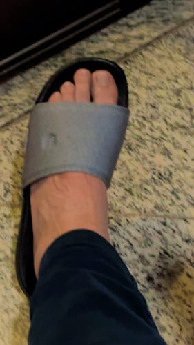 Close-up do confortável chinelo YUOOL SLIDE BEACH CINZA no pé de um cliente.