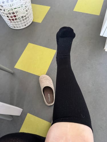 Anmelderens ben med en sort, knælang støttestrømpe på.