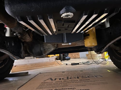 Customer's black SPE Motorsport Oil Pan with silver fins installed under a truck in a garage.