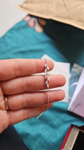 A customer's hand holding the delicate Silver Zircon Ferns Bracelet, showing its zircon-studded leaf motif.