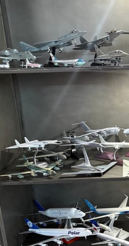 Reviewer's collection of various model airplanes displayed on shelves in a cabinet.