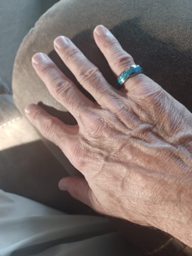 Customer's hand wearing the Vanguard ring, showing its silver tungsten band and blue opal inlay.