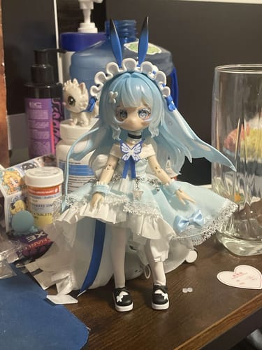 Customer's Vision Reconstruction action figure in a frilly blue dress sitting on a cluttered desk.