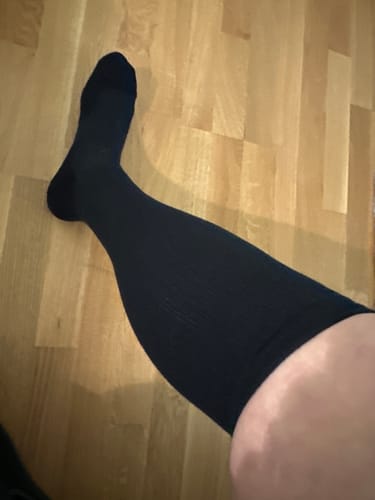 Recensentens ben som visar en svart, knähög Diasocks stödstrumpa mot ett trägolv.