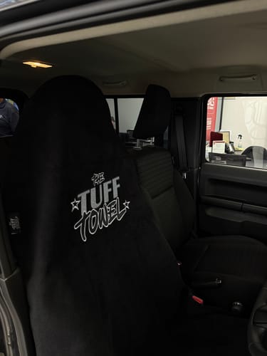 Customer's black Tuff Towel seat cover draped over the driver's seat of a car.