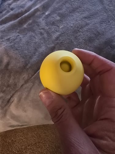 Close-up of a reviewer holding the small, yellow Lem Clitoral Massager.