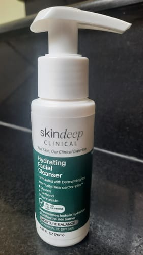 Customer's 70ml white pump bottle of Hydrating Facial Cleanser on a dark countertop.
