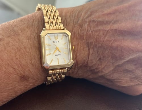 A customer wearing the classic, gold-colored CLAIRE DE MAINS watch on their wrist.