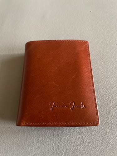 A customer's brown leather Slimstar wallet, shown closed and lying on a flat surface.