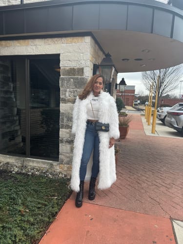 Reviewer standing outside wearing the long, white Faux Fur Plush Long Coat with jeans and boots.