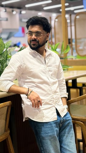 Customer wearing the elegant Barrel Sapphire Blue Rimless Sunglasses while standing indoors in a white shirt.