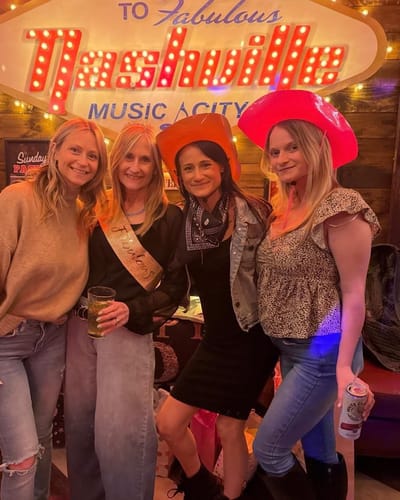 Customer smiles for a photo with three friends at an indoor gathering.
