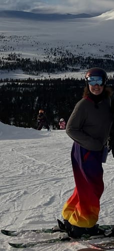 Reviewer skiing on a snowy mountain in the baggy Rainbow Snow Pants.
