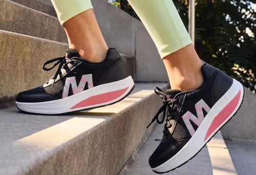 Customer walks up stairs in black Cloud Lift shoes with thick white and pink soles.