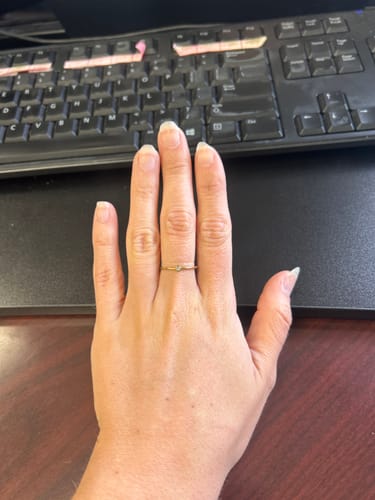 Customer's hand showing the Dainty Birthstone Ring being worn at an office desk.