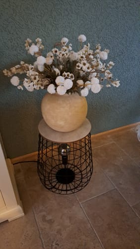 Beoordelaar toont het witte Wax Arrangement in een vaas op een bijzettafel in een kamer.