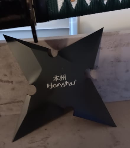 Customer's Large Honshu Black Throwing Star on a surface, showing its sleek design and the Honshu logo.