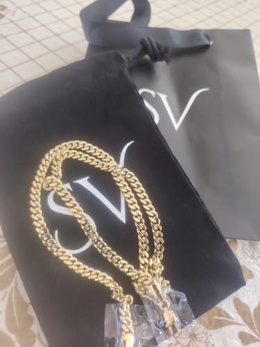 Reseñador mostrando la brillante Cadena Miami Cuban Oro sobre su empaque original de la marca.