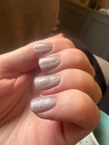 Close-up of a reviewer's hand showing four nails with a shimmery, neat Caramel Cream Shimmer manicure.