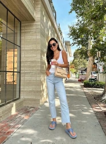 Reviewer standing on a sidewalk wearing light blue Drift sandals with jeans and a white top.