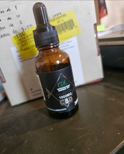 Cliente muestra el frasco de 1000 mg de Green Fit Hemp Oil sobre una mesa.