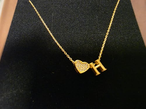 Kunde zeigt die goldene Herz Zirkonia Buchstabenkette mit dem Buchstaben H und einem Zirkonia-Herz.