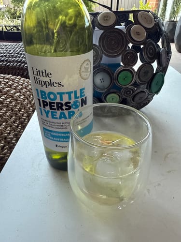 Customer's bottle of Sauvignon Blanc next to a glass of the wine served with ice on a table.