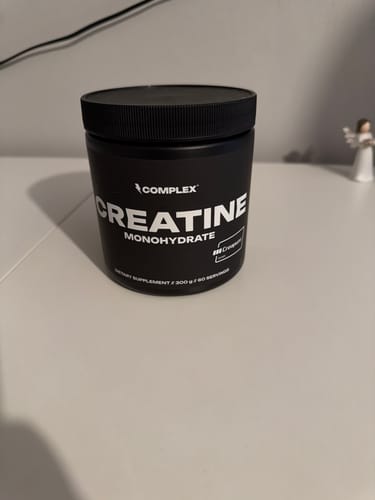 Reviewer's black tub of Complex Creatine Monohydrate supplement sitting on a white desk.