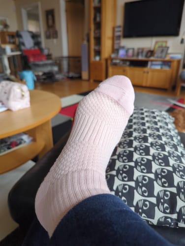 Recensentens fot som vilar i en ljusrosa Diasocks stödstrumpa i ett vardagsrum.