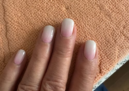 Nahaufnahme der Nägel einer Kundin mit einer glänzenden Ombré-Maniküre, die mit dem UV Top Coat versiegelt ist.
