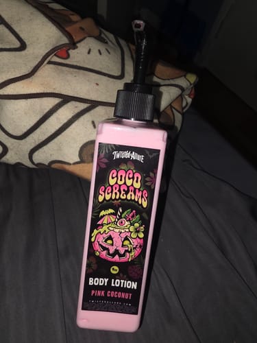 Customer's pink bottle of Coco Screams Body Lotion with a black pump, resting on a dark surface.
