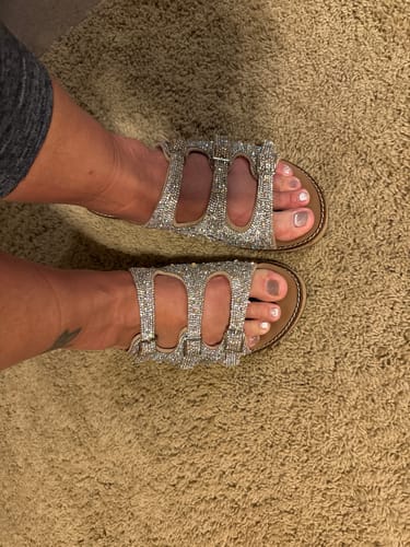 Close-up of a customer's feet wearing the sparkly Corky's Rhinestone Don't Mind Me Wedges on a carpet.