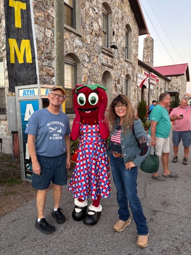Reviewer wearing a blue "My Other Ride Was a P-3 Orion" t-shirt, posing outdoors with a person and a strawberry mascot.