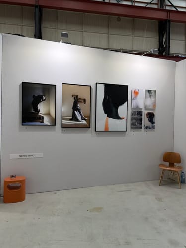 De oranje HKliving Space bijzettafel van een klant, geplaatst in een moderne kunstruimte naast een muur met kunstwerken.