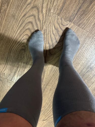 Customer standing in grey Performance Eucalyptus Compression Socks on a wood floor.