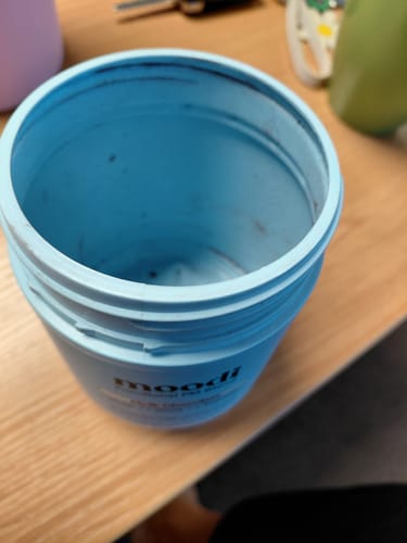 Customer's empty blue tub of Mylk Chocolate PM Blend on a desk.