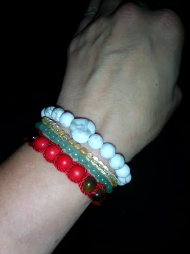 Close-up of a reviewer wearing the white beaded Howlite bracelet stacked with other bracelets on their wrist.