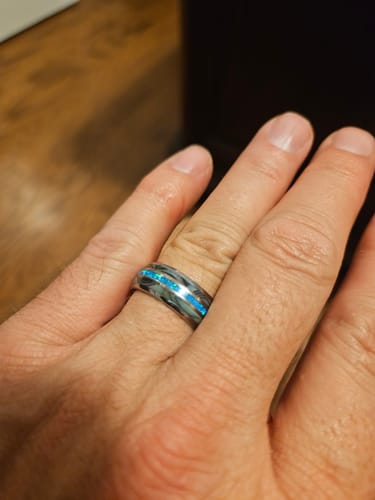 Customer's hand wearing the Vanguard ring, showing the silver tungsten band with abalone and bright blue opal inlays.
