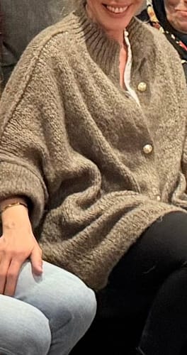 Nahaufnahme einer Kundin, die den kuscheligen, übergroßen Cardigan "CozyGlam" trägt und die goldenen Knöpfe zeigt.