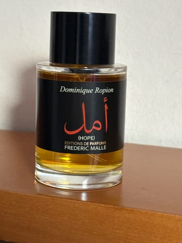 La boccetta del profumo Hope del recensore, con etichetta nera, posata su un mobile in legno.