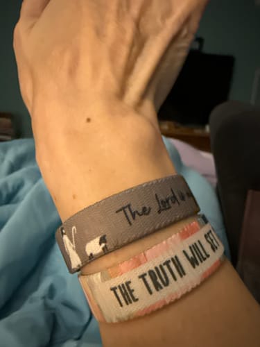 Customer wearing the gray 'The Lord Is My Shepherd' bracelet on their wrist, showing the text and shepherd graphic.