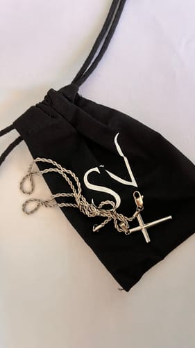 El Crucifix Pendant de un cliente con su cadena, sobre la bolsa de presentación negra.