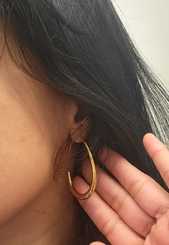 Reviewer wearing a Nica Gold Hoop Earring, holding back dark hair to show the earring's size and fit.