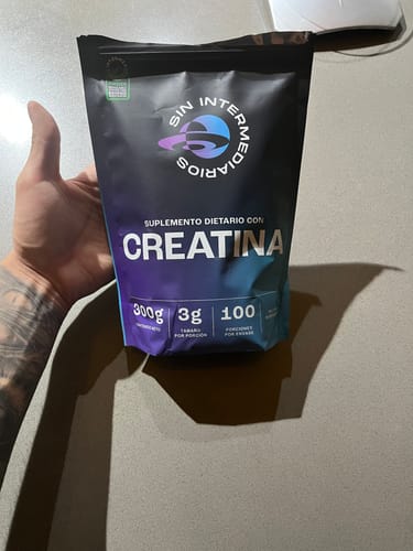Cliente sostiene en su mano el empaque negro de Creatina Monohidrato de 300g.