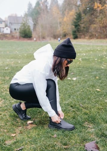 Customer crouching in a park to adjust their black Dry Fit shoes.