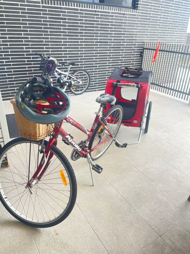 Reviewer's red Pet Trailer Bike attached to their bicycle, with a helmet in the front basket ready for a ride.