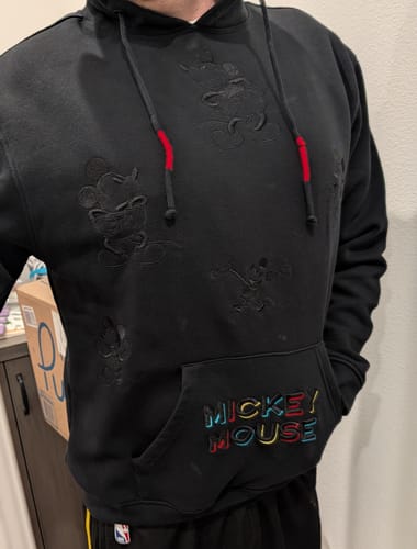 Reviewer shows the fit of the black 'Midnight Mickeys' hoodie, featuring black embroidery and a colorful pocket logo.