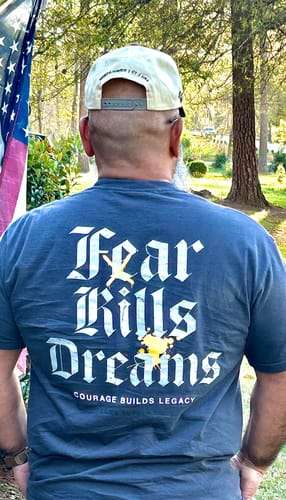 Customer from behind wearing the blue No Fear Pigment Dyed Tee, showing the large 'Fear Kills Dreams' back graphic.